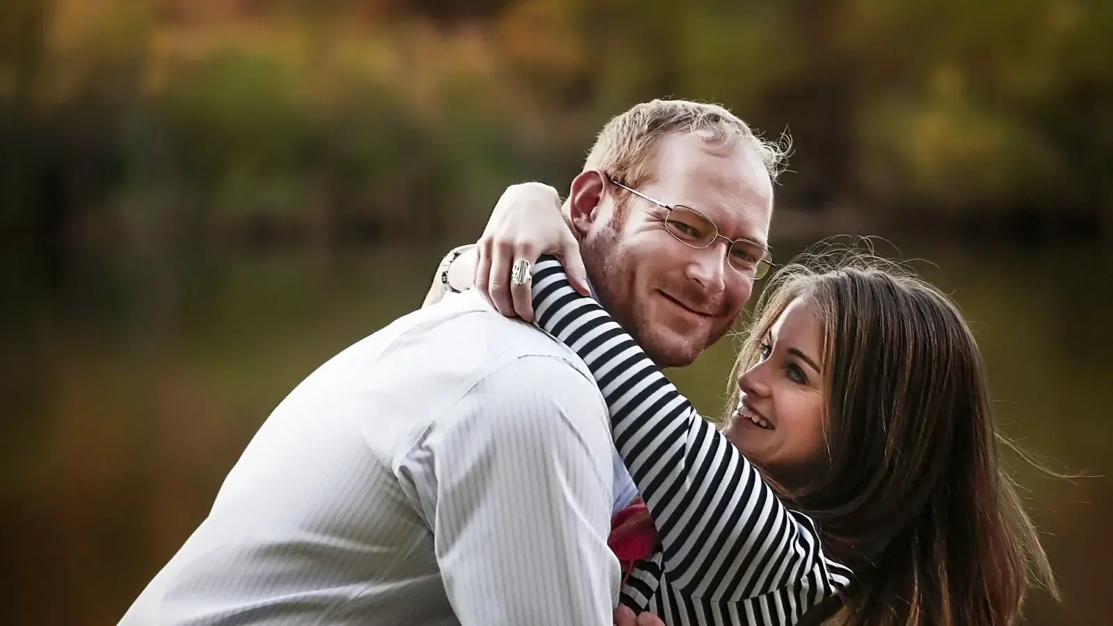 Couple laughing in a close hug outdoors in warm autumn light during a candid portrait session